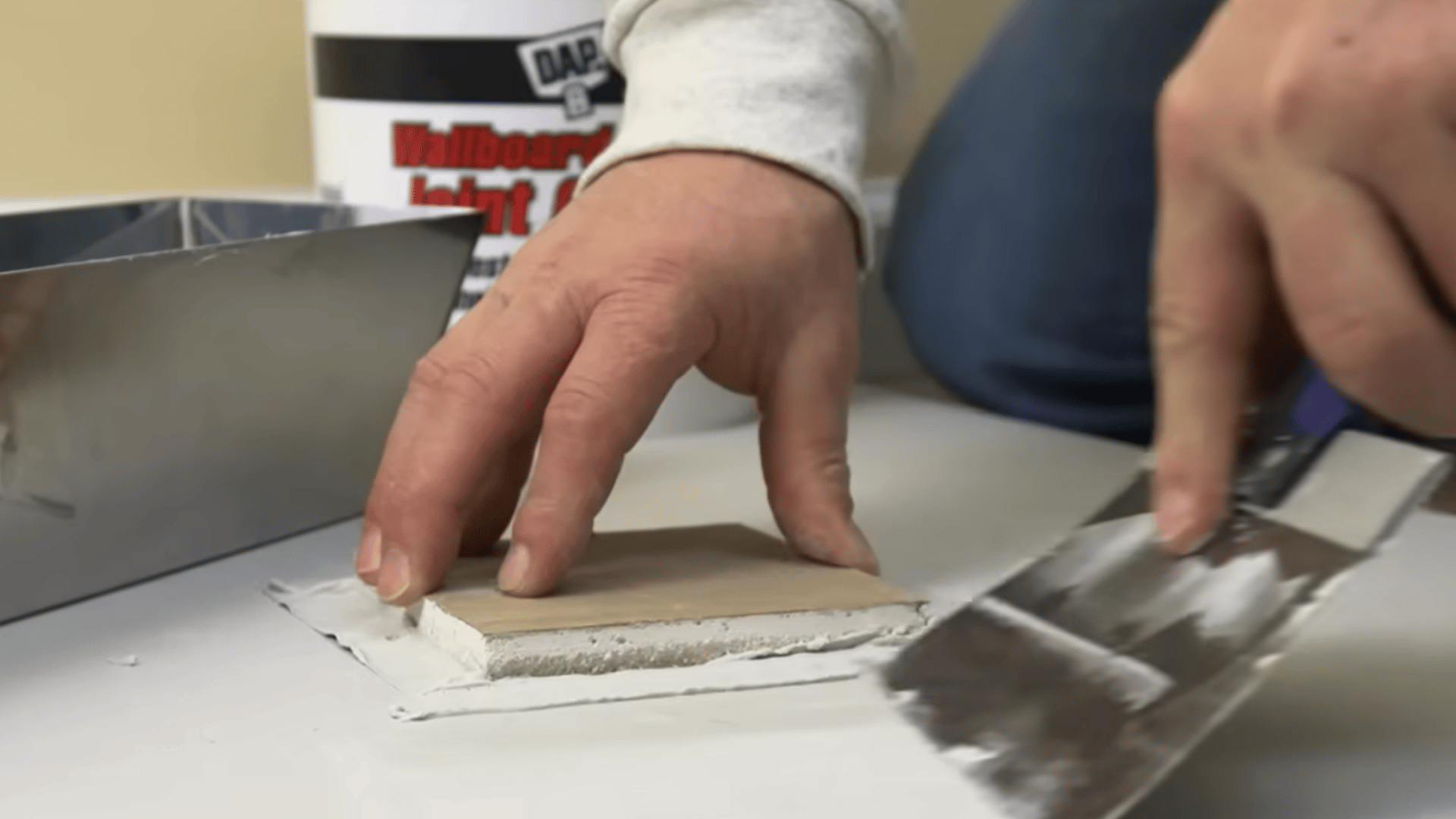Applying joint compound to secure the drywall patch in place.