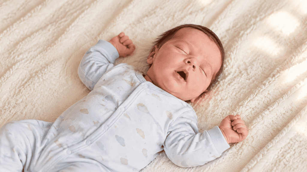 sleeping newborn with slightly open mouth on soft blanket