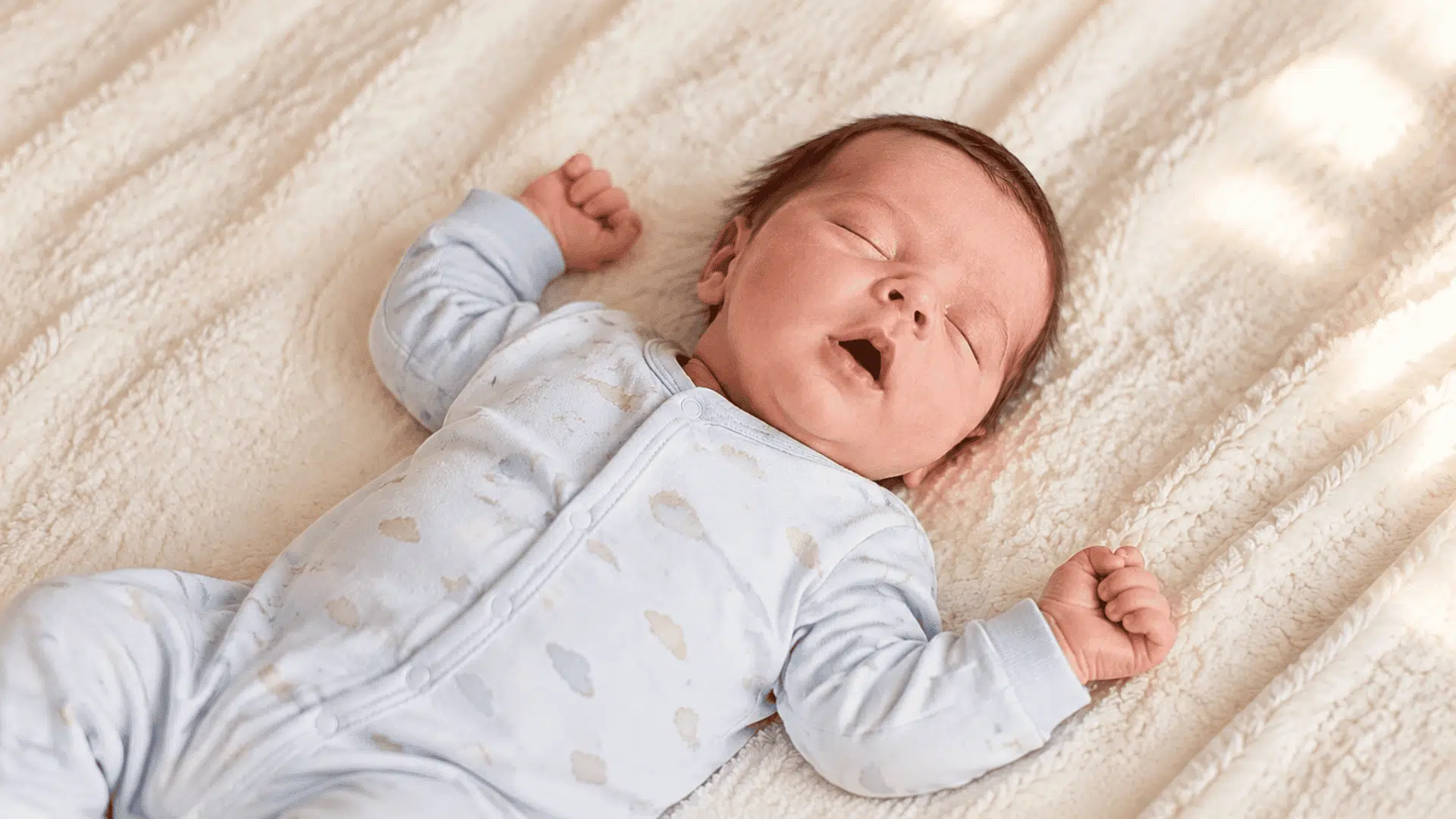 sleeping newborn with slightly open mouth on soft blanket