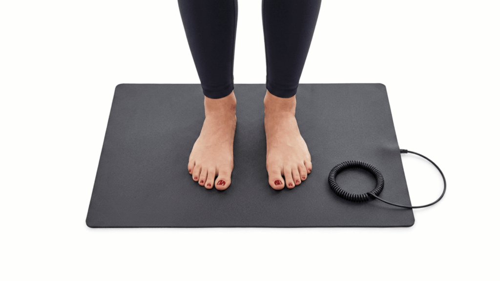 bare feet resting on a black grounding mat with a coiled cord against a white background