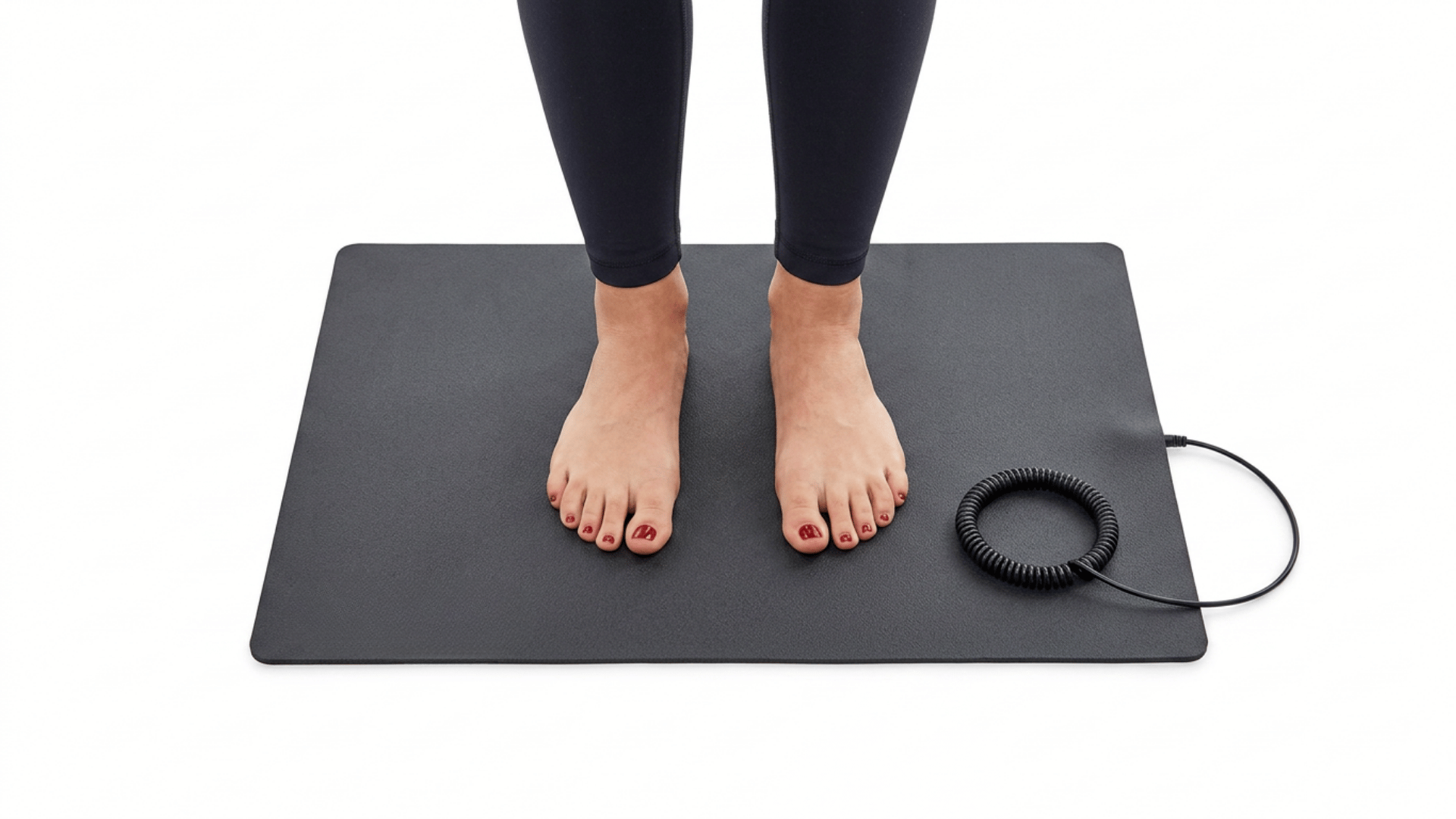 bare feet resting on a black grounding mat with a coiled cord against a white background