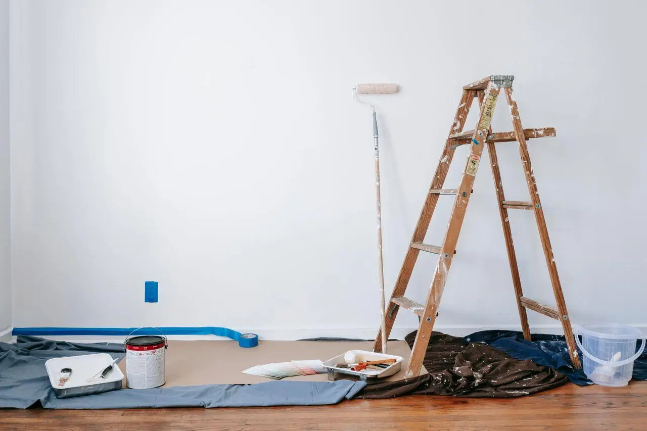 Ladder and painting tools against white wall in preparation for home renovation