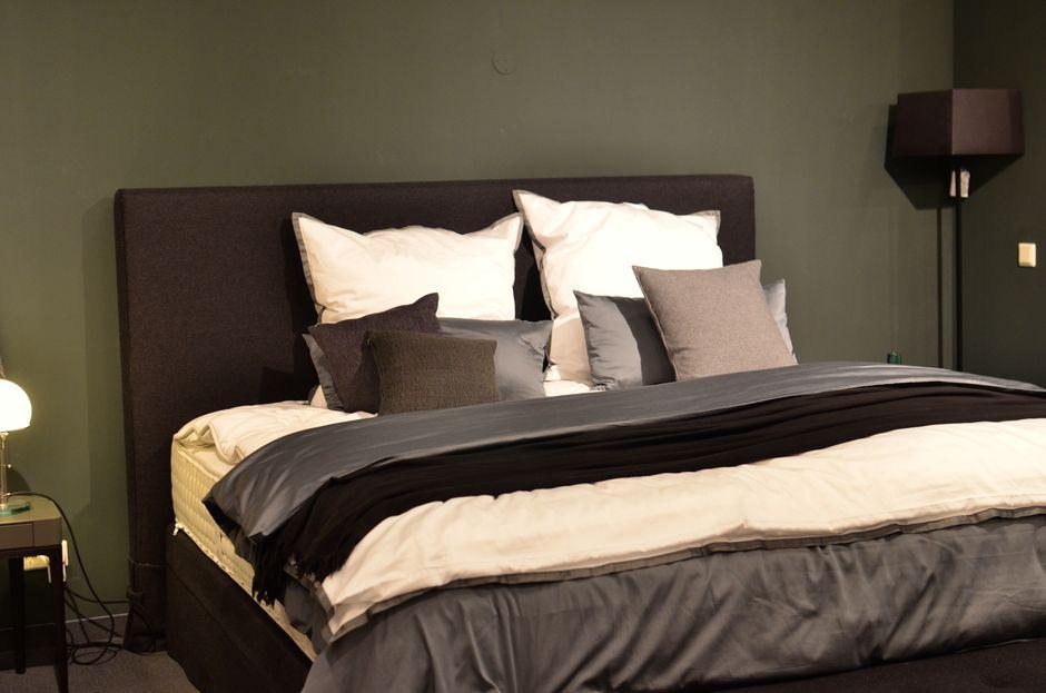 Black upholstered bed with white and gray pillows in a dimly lit bedroom