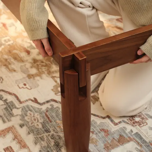 Person assembling wooden furniture piece with interlocking joints on patterned rug