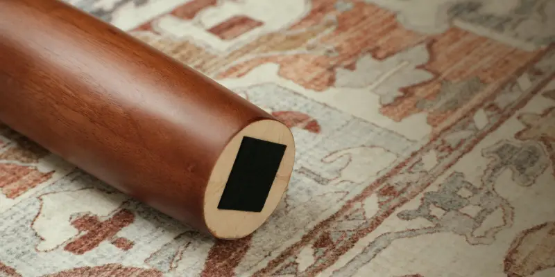 Wooden cylindrical furniture leg on patterned area rug with warm tones