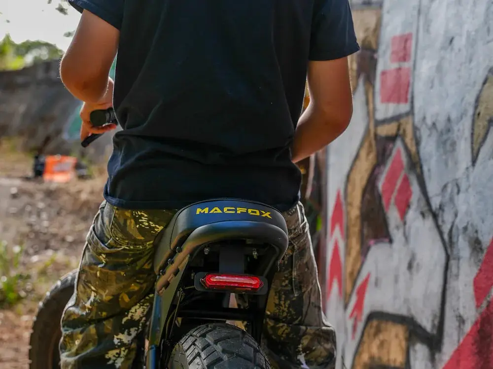 Person wearing camouflage pants riding an electric bike near graffiti wall outdoors