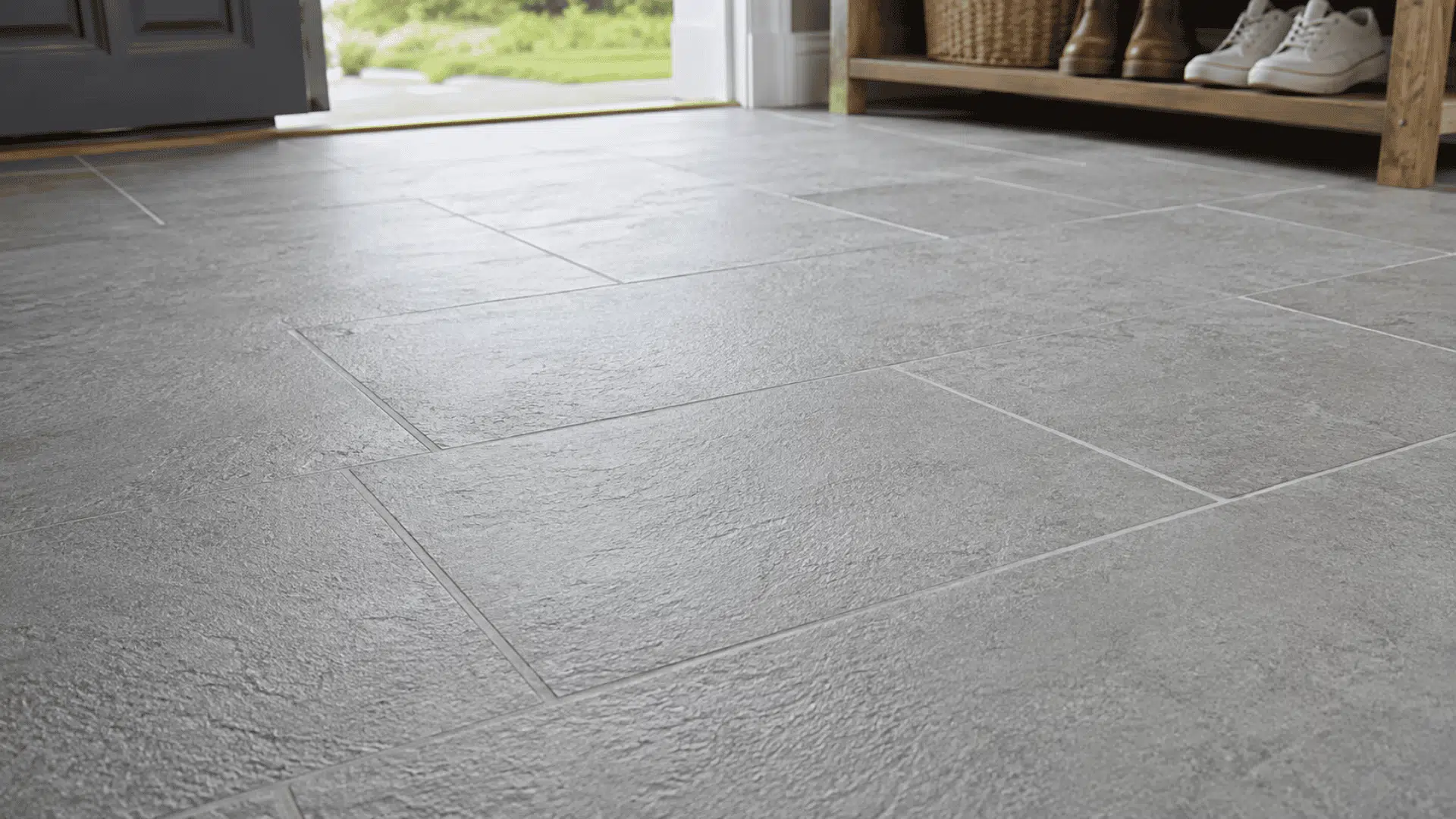 gray slate entryway tiles with fresh grout lines near an open door and wooden shoe rack
