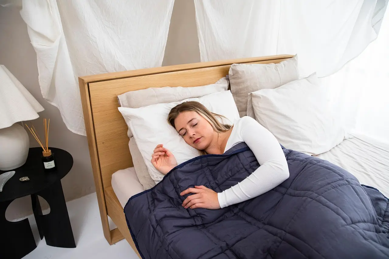 Woman sleeping under a navy blue blanket in a cozy bedroom setting