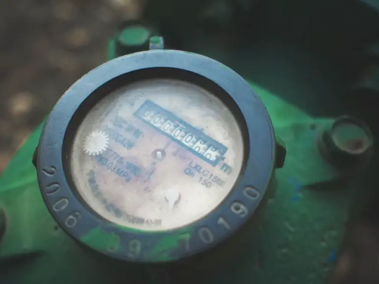 Old water meter on green industrial surface displaying numerical readings